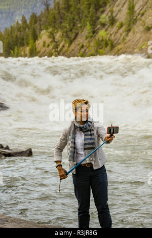 BANFF, AB, Kanada - Juni 2018: Besucher mit einem selfie Stick ein selfie Bild bei den Bow River Falls in Banff zu nehmen. Stockfoto