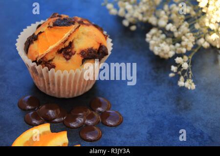 Orange und Schokolade Muffins. Foto auf schiefer Fliesen mit Blumenarrangement als Teil der Stütze zusätzlich mit einigen Zutat Elemente der Muffin Stockfoto
