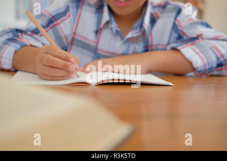 Jungen kleinen asiatischen Kind junge Schüler schreiben Zeichnung auf Notebook. Kind Kinder Hausaufgaben machen. Kindheit Bildung Stockfoto