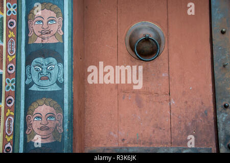 Bhutan, Thimphu. Chong Gia Ca-Tempel. Detail von kunstvoll bemalten Gesichtern um hölzerne Tempel Tür. Stockfoto