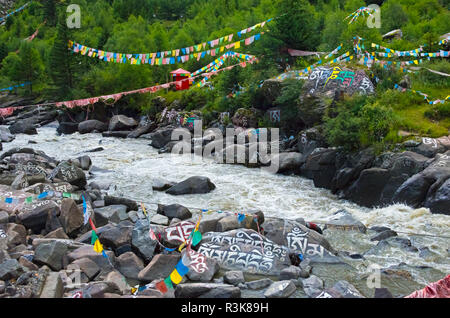 Buddhistische Worte auf Felsen gemalt und betet Fahnen durch den Fluss, Tagong, Western Sichuan, China Stockfoto