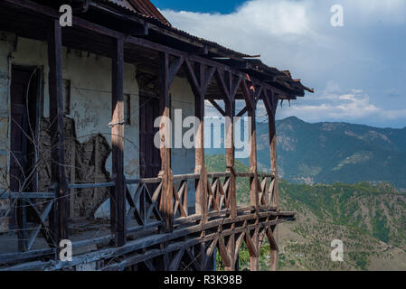 Eine alte verfallene Holz gerahmt traditionelles Haus in Shimla (Simla) mit den Ausläufern des Himalaya im Hintergrund in Himachal Pradesh Stockfoto