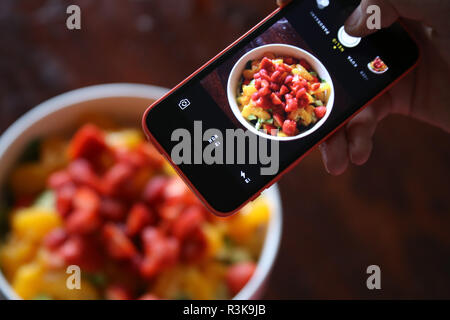 Fotografieren Obst sallad mit verschiedenen Beeren und Früchte mit einem Smartphone Stockfoto