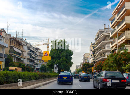 Blick auf die Stadt. Autos auf der Straße. Auf den Seiten der Straße sind Hochhäuser mit großzügigen Balkonen. Großer Kran am Horizont Stockfoto