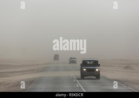 Sand weht über den Highway und Obliteriert Sichtbarkeit auf der Straße in Richtung Walvis Bay, Namibia, was zu extremen gefährlichen Bedingungen für die Fahrer. Stockfoto