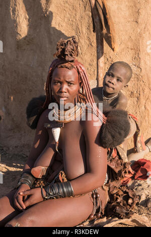 Junge Frau des Chefs und eine Mutter vor ihrer Hütte in einem Himba Dorf in der Nähe von Opuwo. Stockfoto