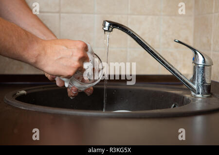 Foto von Seite der Hände des Menschen waschen Transparente Becher in Waschbecken Stockfoto