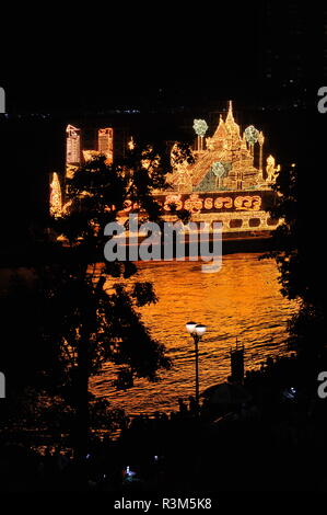 Phnom Penh, Kambodscha. 23. November 2018. Phnom Penh feiert Bon Om Touk, der Kambodschanischen Water Festival, eine beleuchtete Schwimmer seine Reflexion wirft auf dem Tonle Sap Fluss, Baum Silhouette im Vordergrund. © kraig Lieb/Alamy leben Nachrichten Stockfoto