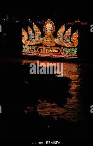 Phnom Penh, Kambodscha. 23. November 2018. Phnom Penh feiert Bon Om Touk, der Kambodschanischen Water Festival. Eine beleuchtete Float, w/Nagas, wirft seine Reflexion über den Tonle Sap Fluss. Baum Silhouette im Vordergrund. © kraig Lieb/Alamy leben Nachrichten Stockfoto