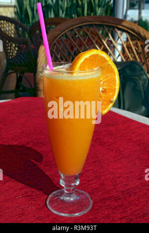 Glas frisch gepressten Orangensaft mit einem Kunststoff Stroh Stockfoto