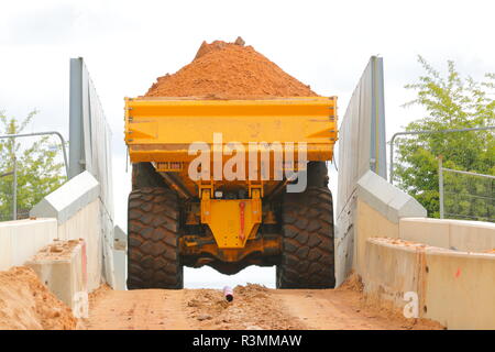 Ein Knickgelenkter Dumper drückt über einem schmalen Eisenbahnbrücke über den Bau von Iport in Rossington, Doncaster, South Yorkshire. Stockfoto