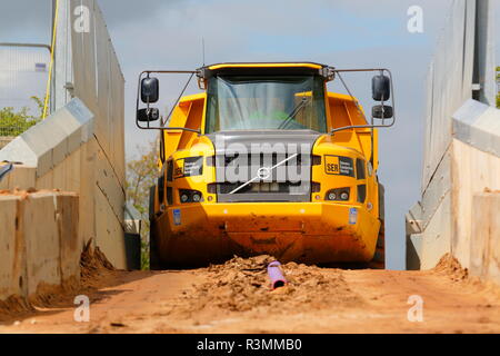 Ein Knickgelenkter Dumper drückt über einem schmalen Eisenbahnbrücke über den Bau von Iport in Rossington, Doncaster, South Yorkshire. Stockfoto