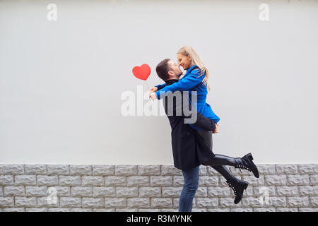 Ein liebevolles Paar in einem Mantel mit Herzen in die Hände. Stockfoto