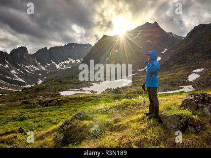 Pass hopping. Frau steht am Damm in Berg Tundra an kalten Morgen. Die Strahlen der Sonne schön Platz beleuchten neben Mädchen Stockfoto