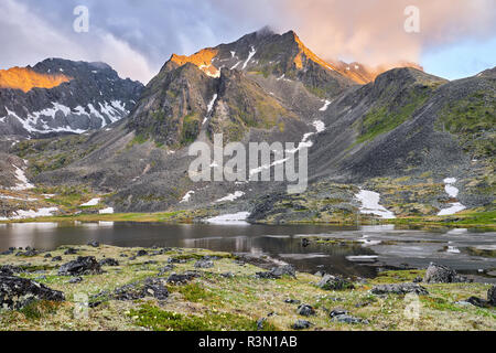 Am frühen Morgen in Berg Tundra im Sommer. Sonnenlicht beleuchtet Bergrücken mit einer goldenen Farbe durch eine trübe Haze. Ostsibirien. Russland Stockfoto