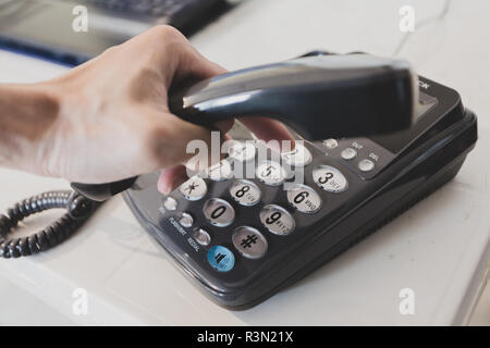 Nahaufnahme der männlichen Hand Telefon Empfänger, während eine Telefonnummer, um einen Anruf zu tätigen, wählen Stockfoto