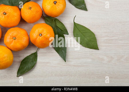 Bündel frische Mandarinen oder Mandarinen auf einem Holztisch und Blätter der Ansicht von oben Stockfoto