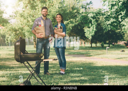 Freunde Grill und dem Mittagessen in der Natur. Paar Spaß beim Essen und Trinken zu einem Pic-nic - glückliche Leute an der Grillparty Stockfoto