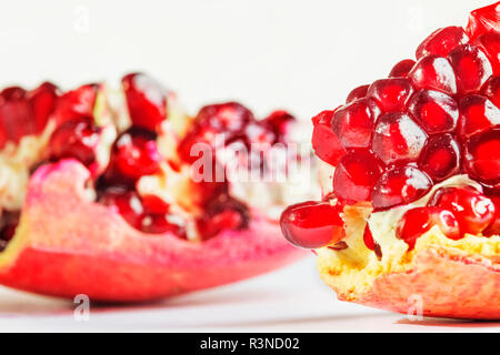 Zwei Granatapfel Abschnitte auf einem weißen Hintergrund, helle rote Samen im Fokus, studio Shot, Vorderansicht Stockfoto