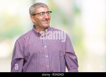 Gut aussehender älterer Mann mit Brille über isolierte Hintergrund entfernt, mit einem Lächeln auf dem Gesicht zu Seite, natürlicher Ausdruck. Lachend zuversichtlich. Stockfoto