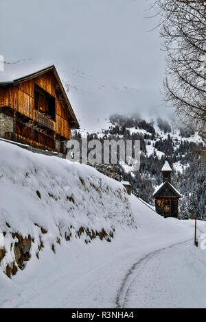 Europa, Österreich, Kals am Großglockner. Kleine Zimmer mit Frühstück und Kapelle auf der schneebedeckten Straße zum Großglockner Stockfoto