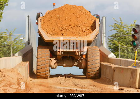 Ein Knickgelenkter Dumper drückt über einem schmalen Eisenbahnbrücke über den Bau von Iport in Rossington, Doncaster, South Yorkshire. Stockfoto