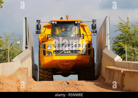 Ein Knickgelenkter Dumper drückt über einem schmalen Eisenbahnbrücke über den Bau von Iport in Rossington, Doncaster, South Yorkshire. Stockfoto