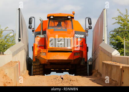 Ein Knickgelenkter Dumper drückt über einem schmalen Eisenbahnbrücke über den Bau von Iport in Rossington, Doncaster, South Yorkshire. Stockfoto