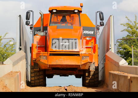 Ein Knickgelenkter Dumper drückt über einem schmalen Eisenbahnbrücke über den Bau von Iport in Rossington, Doncaster, South Yorkshire. Stockfoto