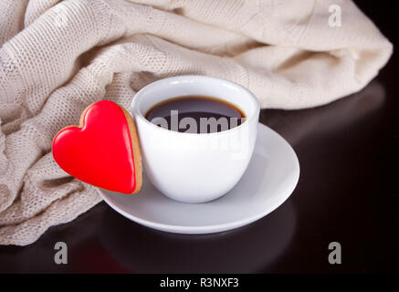Tasse Kaffee und herzförmige einen Cookie auf dem hölzernen Tisch Stockfoto