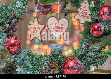 Weihnachten Geschenke oder vorhanden. Bunte Lichter, Globen und Dekorationen im Hintergrund, auf Holzmöbeln im Landhausstil Oberfläche. In Herzform Dekoration aus Holz Stockfoto