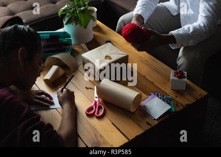 Frau schreiben Name auf geschenkanhänger im Wohnzimmer Stockfoto