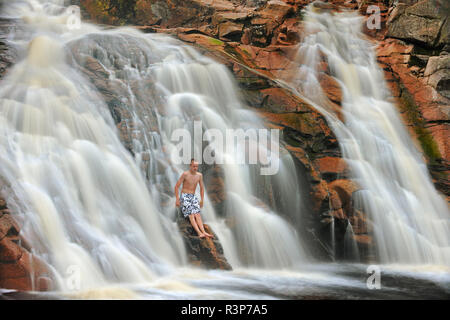 Kanada, Nova Scotia, Cape Breton Highlands National Park. Junge in Mary Ann fällt Wasserfall. Kanada (MR) Stockfoto