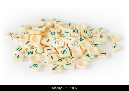 Stapel von Random SCRABBLE-Spiel Buchstabensteine mit Score Wert vermischt, auf weißem Hintergrund. Stockfoto