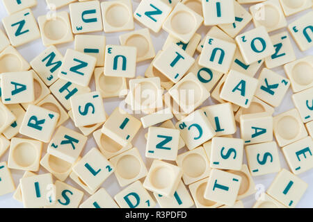 Stapel von Random SCRABBLE-Spiel Buchstabensteine mit Score Wert gemischt, Hintergrund, von oben gesehen. Stockfoto