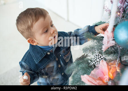 Little boy Standing in der Nähe von Green Christmas Tree Stockfoto