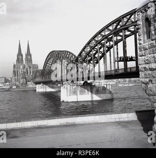 1950er Jahre, historische, Köln, Deutschland, und ein Blick auf die Hohenzollern Brücke den Rhein, mit dem berühmten Twin - spire Koelner Dom in der Island zu erreichen. Stockfoto