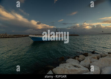 Ein Fischerboot zurück zum Hafen bei Sonnenuntergang in Spanien. Stockfoto