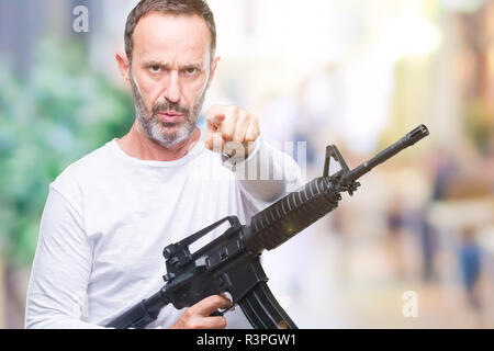 Mittleres Alter senior hoary kriminellen Mann mit Pistole Waffe über isolierte Hintergrund zeigt mit dem Finger auf die Kamera und an Sie, Hand unterzeichnen, positiven Ein Stockfoto