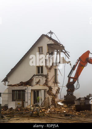 Planierraupe Bagger den Abriss alter Gebäude an einem nebligen Tag Stockfoto