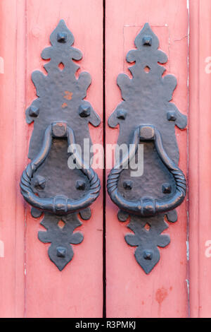 Vintage metallische Türgriffe Schwarz auf einem hölzernen roten Holztür Hintergrund gemalt, Konzept der authentische Objekte, kopieren, close-up. Stockfoto