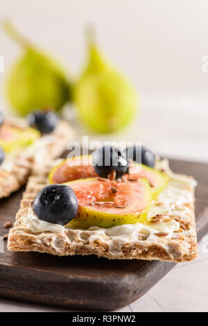 Vorspeise oder Crostini mit Multigrain crispread mit Frischkäse und frische Feigen Schichten auf einem Holzbrett. Köstliche Vorspeise ideal als Aperitif. Stockfoto