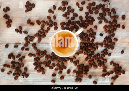 Leere Tasse mit Resten von Espresso und gerösteten Kaffeebohnen auf Holz Stockfoto