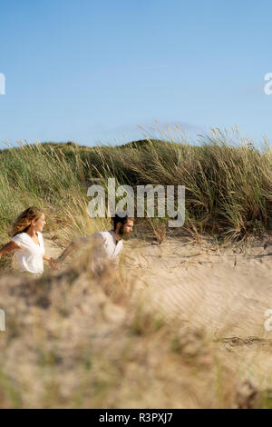 Ein junges Paar, das Spaß in den Dünen, laufen Hand in Hand Stockfoto