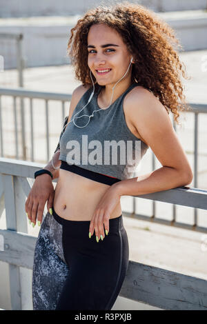 Portrait von lächelnden Jungen athletische Frau Ohrstöpsel tragen Stockfoto