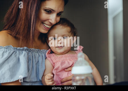 Die Mutter, die ihr Baby Milch in der Flasche Stockfoto