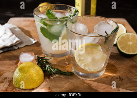 Gläser Gin Tonic mit Limette, Minze, Rosmarin und Eis und mit Zitrone, Rosmarin und Eis Stockfoto