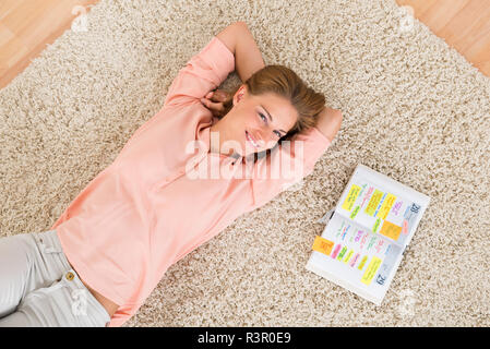 Frau mit Tagebuch liegen auf dem Teppich Stockfoto