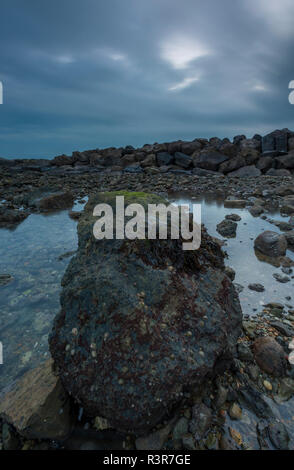 Einen großen Felsen am Strand bei Sonnenuntergang auf der Isle of Wight in einem stimmungsvollen und schönen Marine auf der Insel Küste. Stockfoto