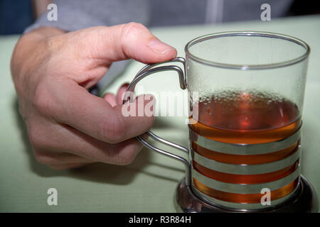 Hand mit einem heißen Glas Tee Stockfoto